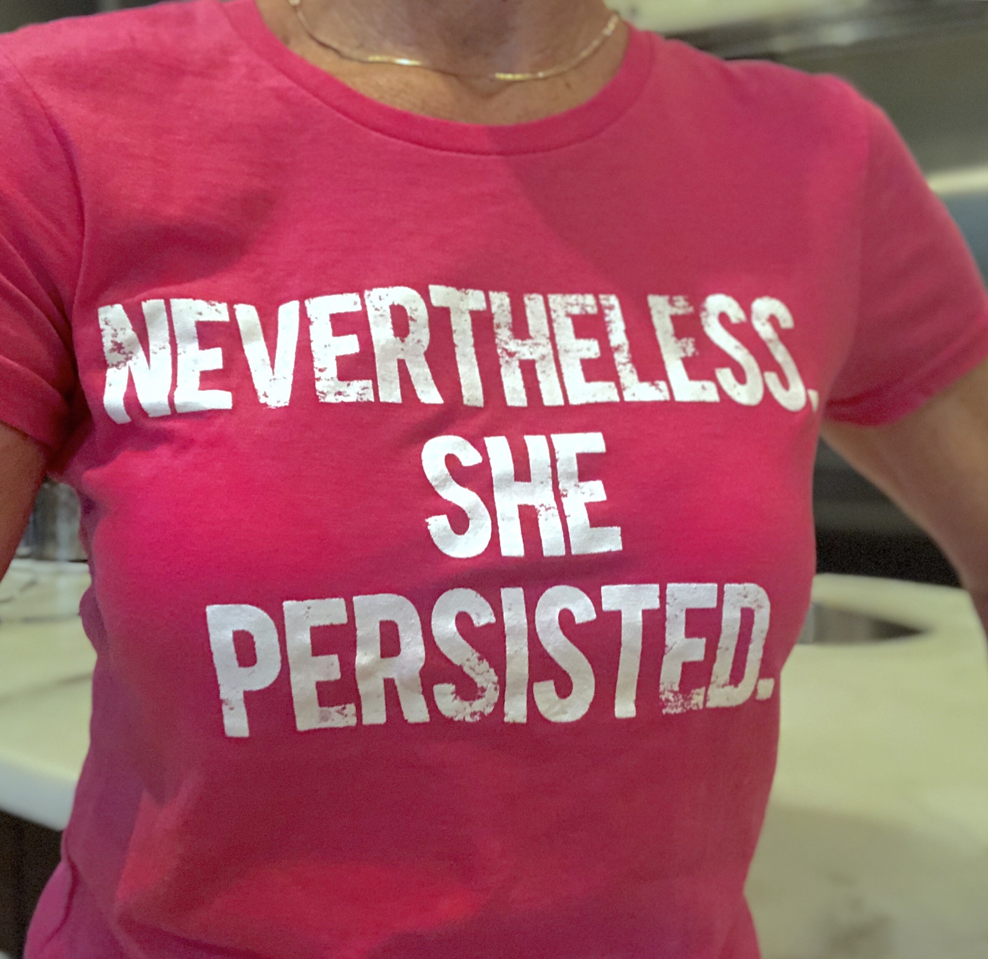 A woman wearing a shirt that says nevertheless she persisted